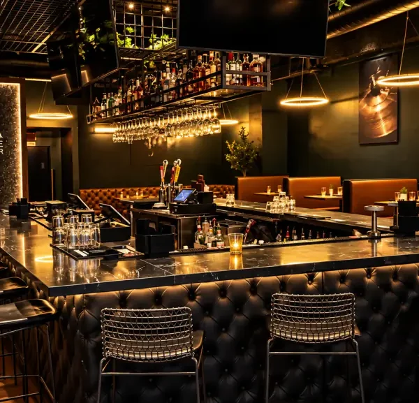 The bar at Brugada Kitchen & Bar: black marble top, tufted leather front and wire stools