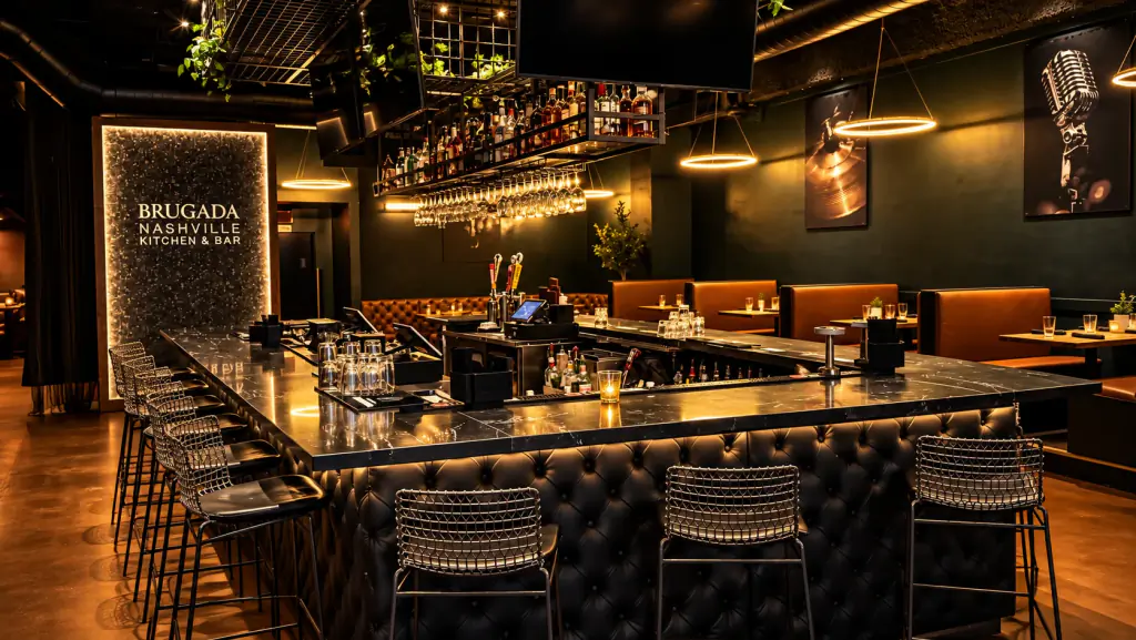 The bar at Brugada Kitchen & Bar: black marble top, tufted leather front and wire stools